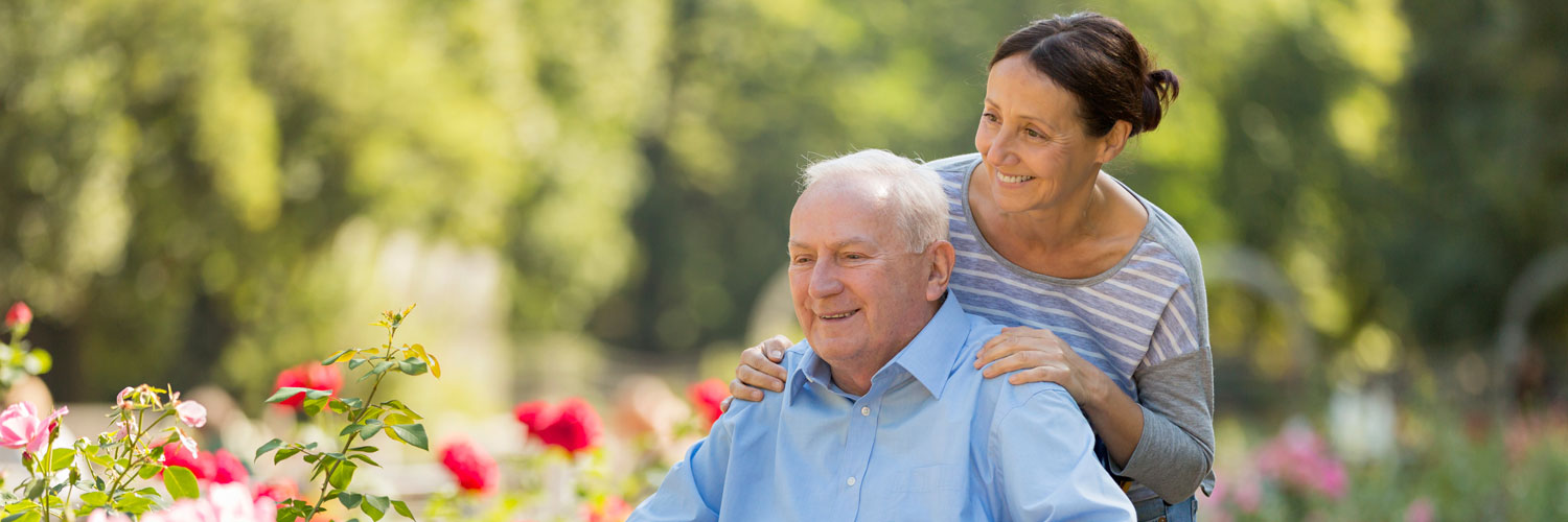 Caregiver and elderly man looking at flowers